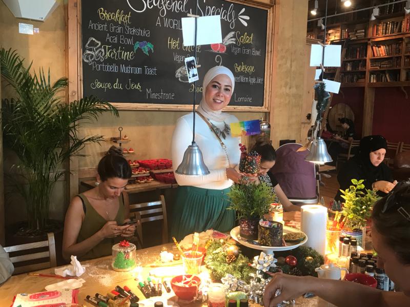 Merit presenting a painted candle jar at her Bath & Body Works upcycling workshop in Dubai